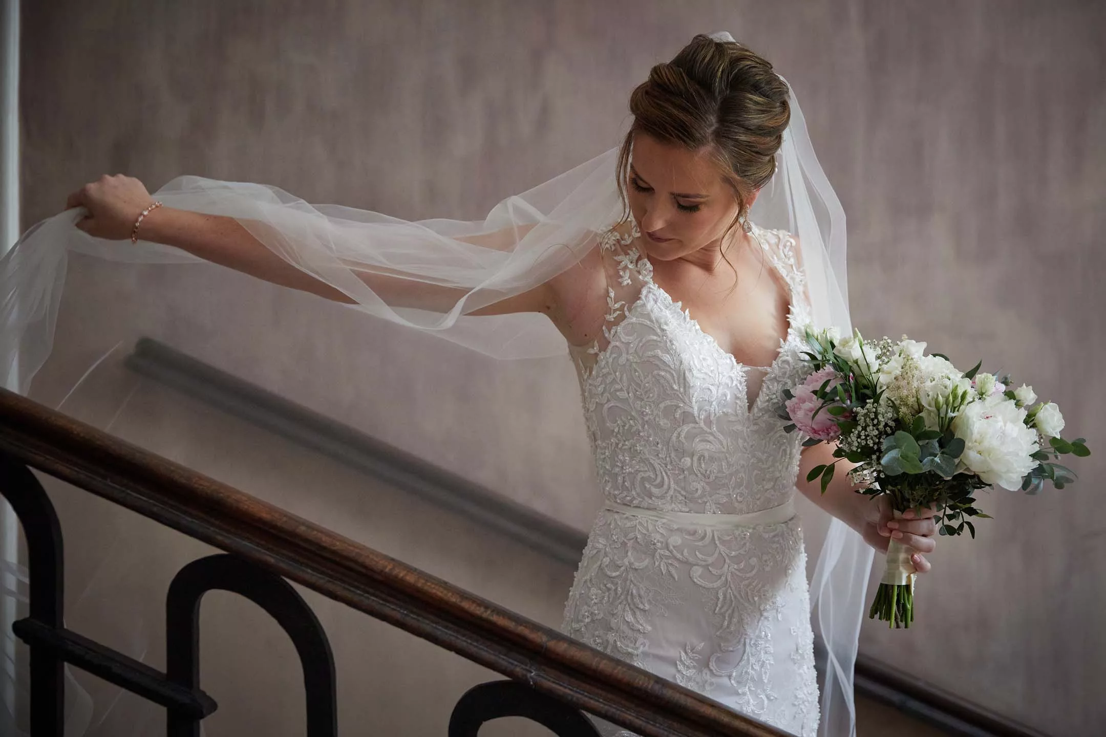 La mariée descendant une escalier en déployant son voile, reportage de mariage à Pau par Andres Rodriguez, photographe.